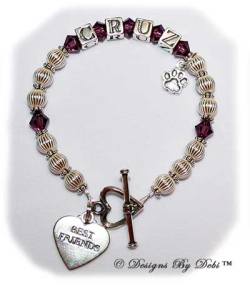 Designs by Debi Handmade Jewelry Ali Style Pet Keepsake Bracelet in the Corrugated with Antiqued Daisies bead combination, Amethyst (February) crystals, a heart toggle clasp, Best Friends heart charm and additonal Paw charm added at the end of the name.