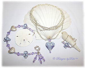 Designs by Debi Handmade Jewelry Aloha Collection Lavender Necklace, Bracelet and Anklet Set. Covertible style necklace is long figaro chain with a lavender aloha floral handmade lampwork heart pendant. Bracelet features lavender aloha floral handmade lampwork beads, bali silver embossed floral heart pillows, swarovski crystal violet and clear crystal bicones, dangles, a petite sterling floral toggle clasp and matching anklet.