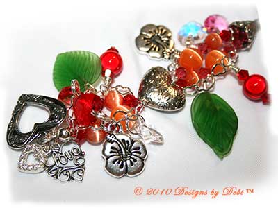 Valentine Hearts for Haiti One-of-a-Kind Handmade Bracelet made with a gorgeous artisan handmade lampwork bead, a red heart-shaped bead with pink and orange hibiscu, red, yellow and lavender flowers and green leaves; Bali fine silver heart-shaped pillow beads with embossed flowers, fancy bead caps with a swirling filigree pattern and heart toggle; Swarovski bicone and heart crystals in crystal, crystal AB, light siam, padparadscha and rose; orange cat's eye beads; sterling silver heart link chain; TierraCast hibiscus charms; red miracle beads and green glass leaves. Close-up.