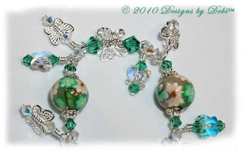 Spring Butterflies One-of-a-Kind Handmade Bracelet made with artisan handmade polymer clay round beads with green and white flowers and green butterflies, sterling silver butterflies, Swarovski crystal butterflies and Swarovski crystal AB and light emerald bicones with a sterling silver butterfly toggle style clasp. Close-up.