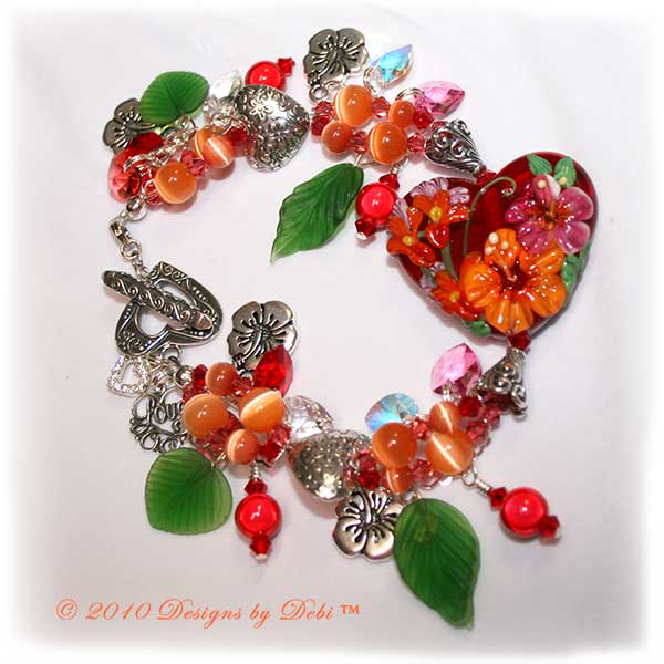 Valentine Hearts for Haiti One-of-a-Kind Handmade Bracelet made with a gorgeous artisan handmade lampwork bead, a red heart-shaped bead with pink and orange hibiscu, red, yellow and lavender flowers and green leaves; Bali fine silver heart-shaped pillow beads with embossed flowers, fancy bead caps with a swirling filigree pattern and heart toggle; Swarovski bicone and heart crystals in crystal, crystal AB, light siam, padparadscha and rose; orange cat's eye beads; sterling silver heart link chain; TierraCast hibiscus charms; red miracle beads and green glass leaves.