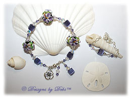 Designs by Debi Handmade Jewelry Aloha Collection Purple Bangle Bracelet and Anklet Set. Features gorgeous purple hibiscus handmade lampwork beads, violet cat's eye cubes, silver filigree bead caps, swarovski crystal tanzanite and crystal ab bicones, a silver hibiscus charm, dangles, a magnetic clasp and matching anklet.
