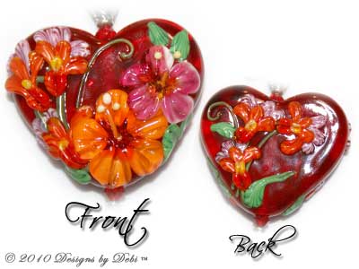 Valentine Hearts for Haiti One-of-a-Kind Handmade Bracelet made with a gorgeous artisan handmade lampwork bead, a red heart-shaped bead with pink and orange hibiscu, red, yellow and lavender flowers and green leaves; Bali fine silver heart-shaped pillow beads with embossed flowers, fancy bead caps with a swirling filigree pattern and heart toggle; Swarovski bicone and heart crystals in crystal, crystal AB, light siam, padparadscha and rose; orange cat's eye beads; sterling silver heart link chain; TierraCast hibiscus charms; red miracle beads and green glass leaves. Close-up.