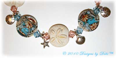 Designs by Debi Jewelry for Charity Piece for July 2010 to raise money for The Deepwater Horizon Memorial Fund. A one-of-a-kind artisan handmade bracelet with blue and beige lentil-shaped ocean within handmade glass beads, handmade glass sand dollar beads, swarovski crystal aquamarine and light peach bicones, sterling silver round beads, sterling silver sand dollar charms, sterling silver shell charms, sterling silver starfish charms, a swarovski crystal aquamarine starfish and a shiana thai sterling silver sand dollar toggle clasp. OOAK