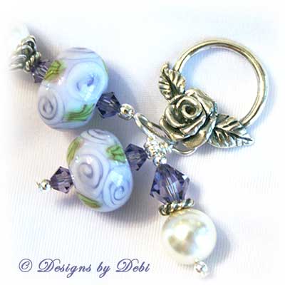 Designs by Debi Jewelry for Charity Piece for May 2010 to raise money for The Cystic Fibrosis Foundation. A one-of-a-kind artisan handmade bracelet with round handmade glass beads adorned with purple roses and green leaves, swarovski crystal tanzanite bicones, white swarovski pearls, sterling silver rose beads, sterling silver rose spacer beads and a sterling silver roses toggle clasp. OOAK