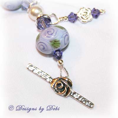 Designs by Debi Jewelry for Charity Piece for May 2010 to raise money for The Cystic Fibrosis Foundation. A one-of-a-kind artisan handmade bracelet with round handmade glass beads adorned with purple roses and green leaves, swarovski crystal tanzanite bicones, white swarovski pearls, sterling silver rose beads, sterling silver rose spacer beads and a sterling silver roses toggle clasp. OOAK