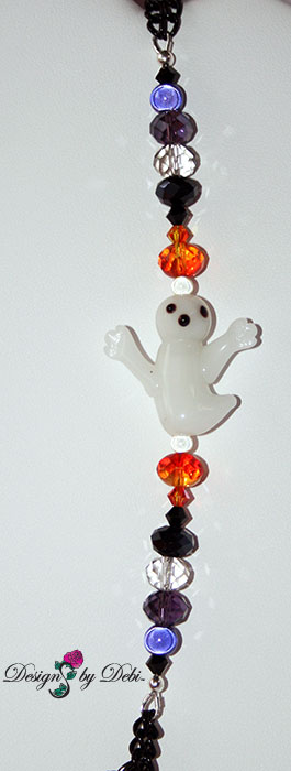 Ghost segment of Designs by Debi Handmade Jewelry for Charity Set October 2012 to benefit Born This Way Foundation. A one of a kind Halloween theme lariat necklace and earrings made with Swarovksi and other crystals in black, black diamond, fire opal and purple velvet, a unique Haunted House focal piece, black curb chain, a white glass ghost, haunted house, spider web and padlock charms, a white glass bone pendant bead and a large silver skeleton key. Copyright Designs by Debi.