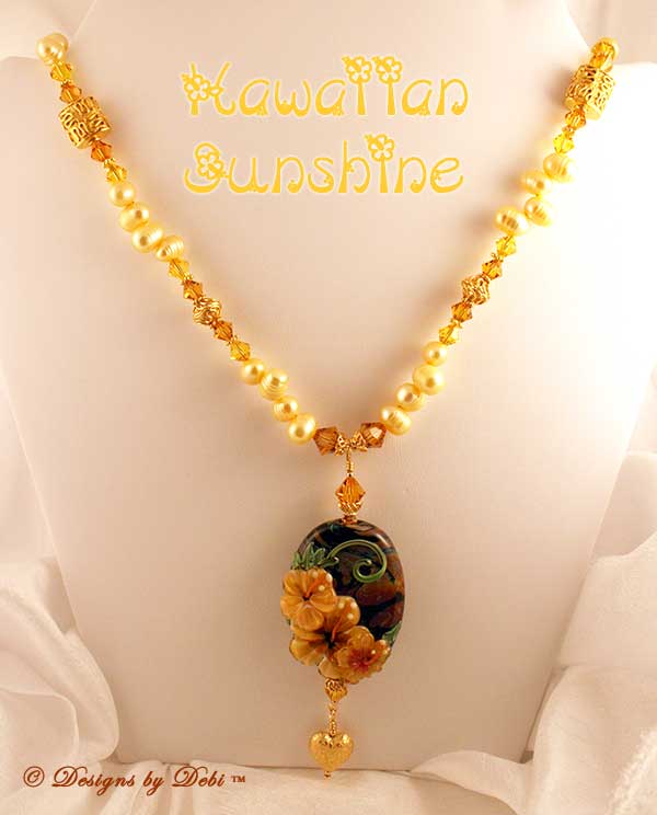 Designs by Debi September 2011 Jewelry for Charity Necklace Hawaiian Sunshine. A one of a kind necklace with a golden hibiscus handmade lampwork focal bead; golden yellow, dancing freshwater pearls, Bali vermeil squiggle pillows, filigree bicones and bead caps, daisy spacers, diamond-shaped toggle clasp and puffy heart dangle, and Swarovski crystal bicones in topaz and light topaz. One-of-a-kind OOAK
