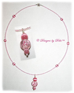 Designs by Debi Handmade Jewelry Aloha Collection Pink Aloha Floral and Cat's Eye Necklace featuring a pink shimmery aloha floral bead pendant, pink round cat's eye beads, shimmery pink seed beads and a magnetic clasp.