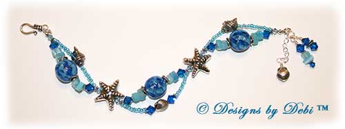 Designs by Debi Jewelry for Charity Piece for August 2010 to raise money for The Donald Paterson Recovery Fund. A one-of-a-kind artisan handmade bracelet with blue ribbon waves round handmade glass beads, thai silver starfish beads, swarovski crystal aquamarine and capri blue bicones, bali sterling silver spacer beads, sterling silver conch shells, tierracast silver scallop shells, light blue cat's eye chips, seed beads and a bali sterling silver hook and eye clasp with extender chain. OOAK one of a kind