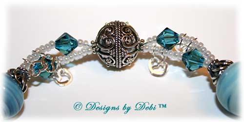 Designs by Debi Handmade Jewelry January 2011 Jewelry for Charity Piece Caribbean Hearts. Teal, white and sterling silver one of a kind lampwork bracelet to raise money for the National Cervical Cancer Coalition. The bracelet has a heart theme...handmade lamwork beads swit=rled in white and caribbean blues, swarovski teal indicolite bisone crystals, tiny pearly white seed beads, round Bali beads with a repeating heart design, sterling silver heart link chain and a sterling silver heart toggle. OOAK