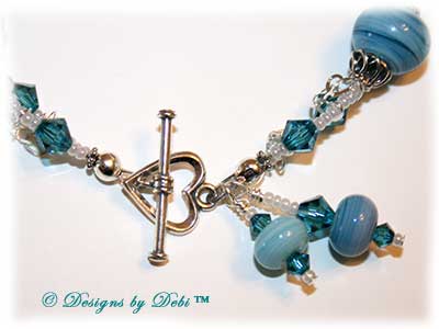 Designs by Debi Handmade Jewelry January 2011 Jewelry for Charity Piece Caribbean Hearts. Teal, white and sterling silver one of a kind lampwork bracelet to raise money for the National Cervical Cancer Coalition. The bracelet has a heart theme...handmade lamwork beads swit=rled in white and caribbean blues, swarovski teal indicolite bisone crystals, tiny pearly white seed beads, round Bali beads with a repeating heart design, sterling silver heart link chain and a sterling silver heart toggle. OOAK