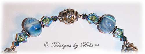 Designs by Debi Jewelry for Charity Set July 2011 Swirling Ocean Surf to benefit the American Red Cross. A beautiful, one of a kind handmade lampwork bracelet and earrings set in swirling blue, white and hints of green, swirled Bali silver beads, twisted rings and elegantly scrolled toggle clasp accented with Swarovski crystal bicones in aquamarine ab2x and montana ab2x. OOAK © Designs by Debi All Rights Reserved