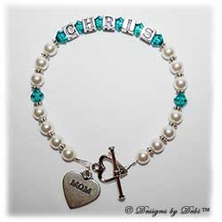 Designs by Debi Handmade Jewelry Keepsake Bracelet in the Ali Style Pearls with Antiqued Daisies bead combination with Blue Zircon (December) crystals, a heart toggle clasp and Mom heart charm. Mother's Bracelet