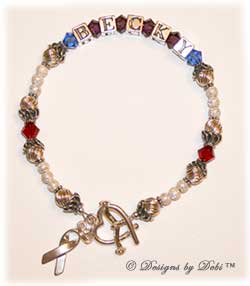 Designs by Debi Handmade Jewelry Memorial Keepsake Bracelet in the Marisol Style Twist and Stardust bead combination with Sapphire (September), Amethyst and Siam crystals, an Awareness Ribbon Heart toggle clasp and Awareness Ribbon charm.